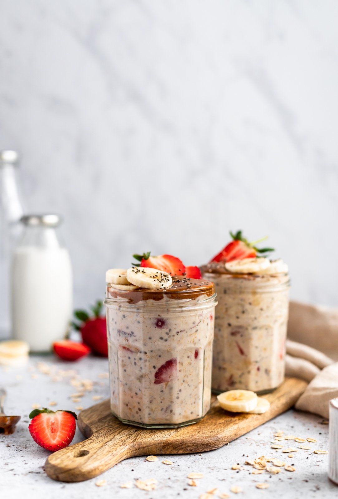 healthy strawberry banana overnight oats in two jars on a wooden board
