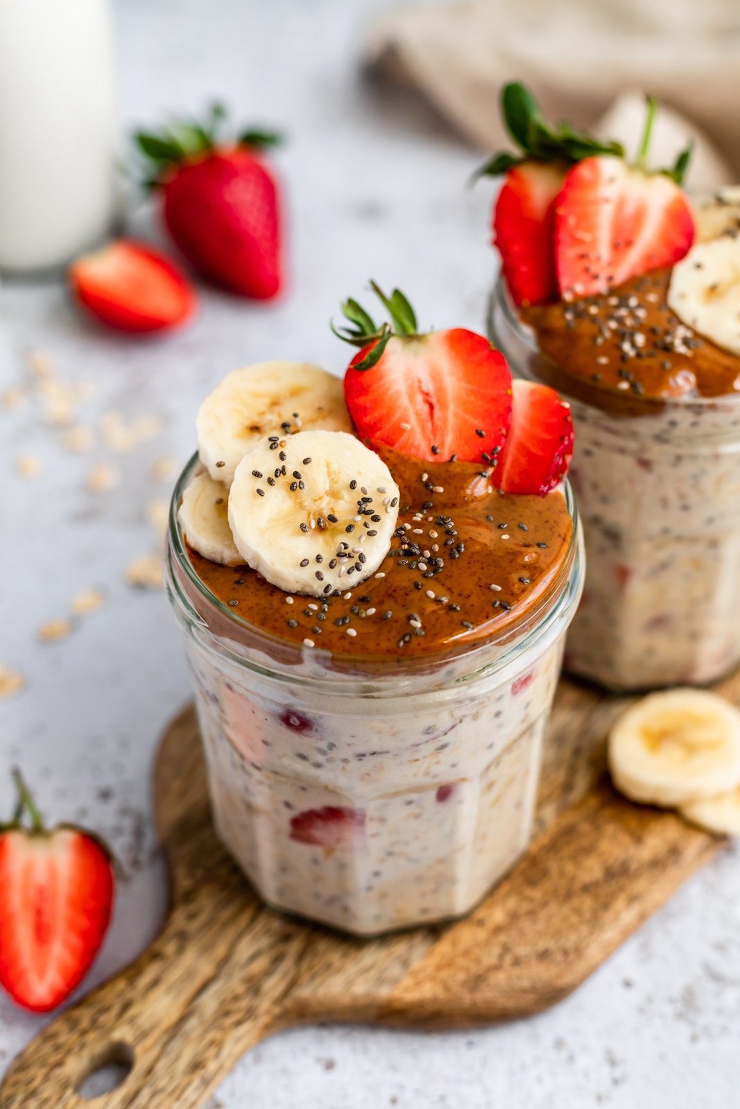 strawberry banana overnight oats in jars topped with almond butter