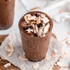 creamy vegan coconut chocolate zucchini smoothie in a glass topped with coconut