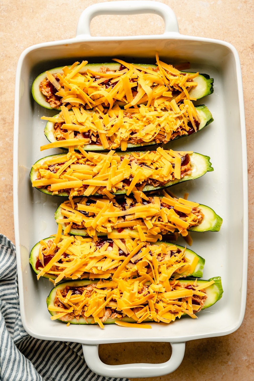 unbaked bbq chicken zucchini boats topped with shredded cheese