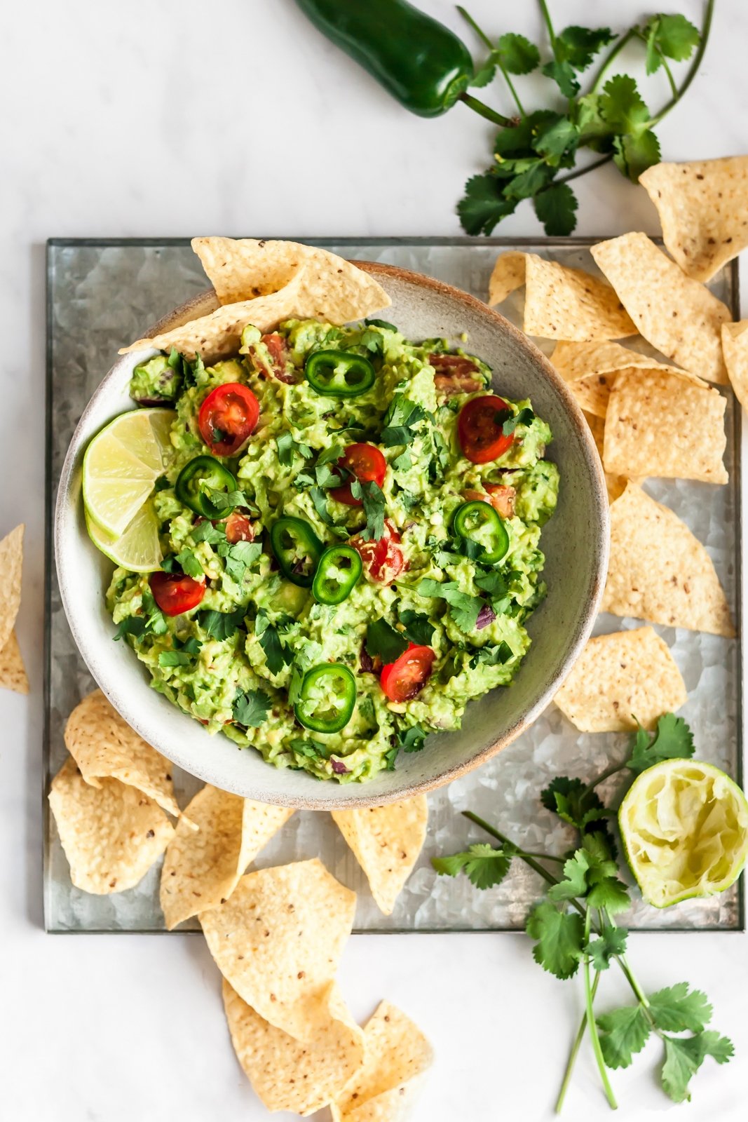 the best guacamole in a bowl with chips and cilantro on the side