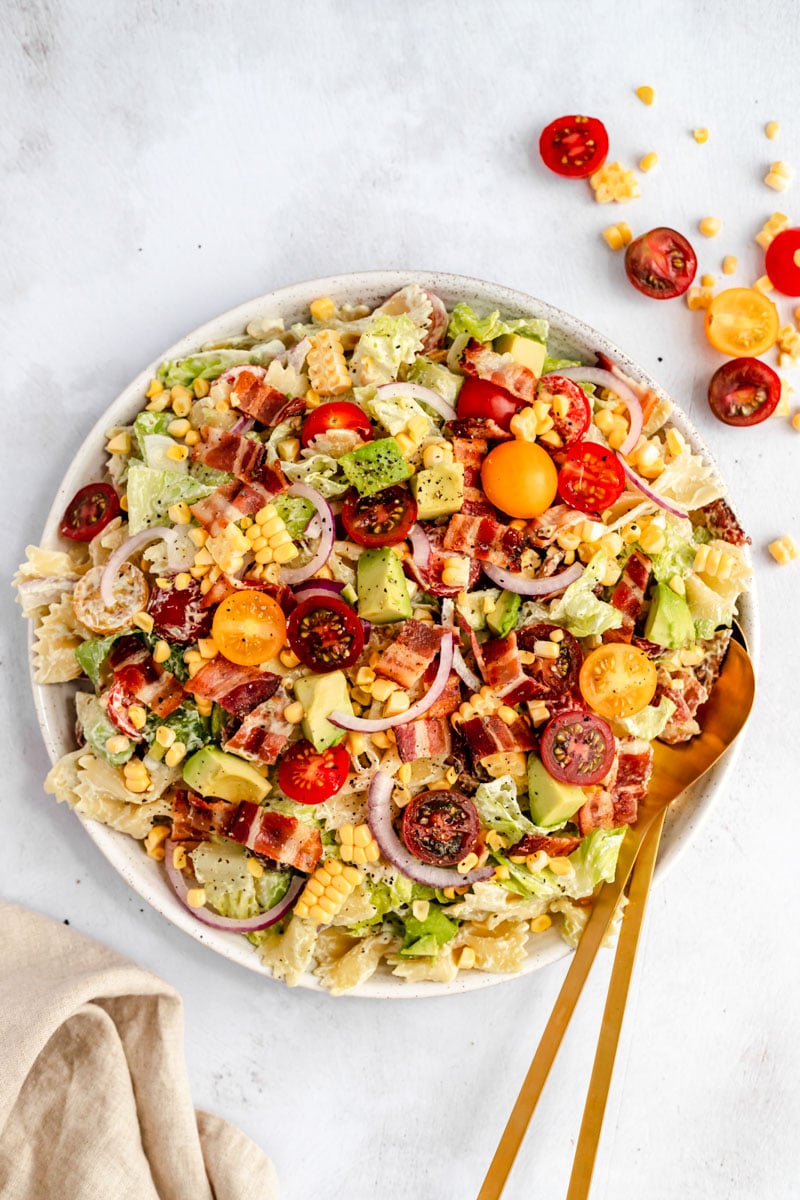 healthy BLT pasta salad in a bowl with golden spoons