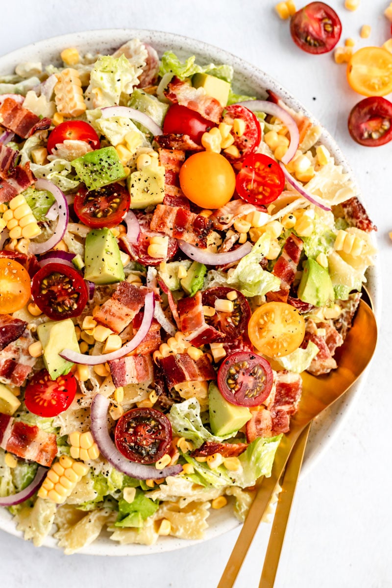 BLT pasta salad recipe in a bowl with gold salad spoons