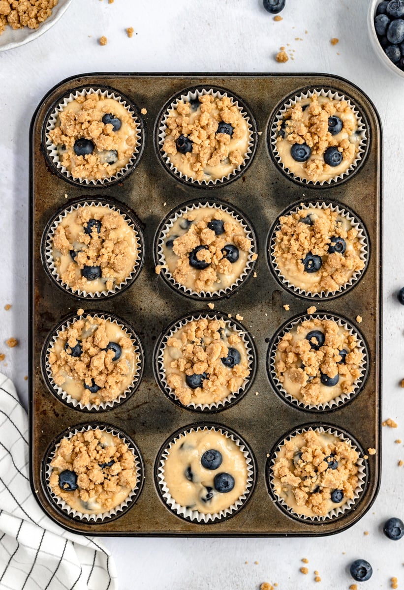 best blueberry muffins with crumb topping in a muffin tin