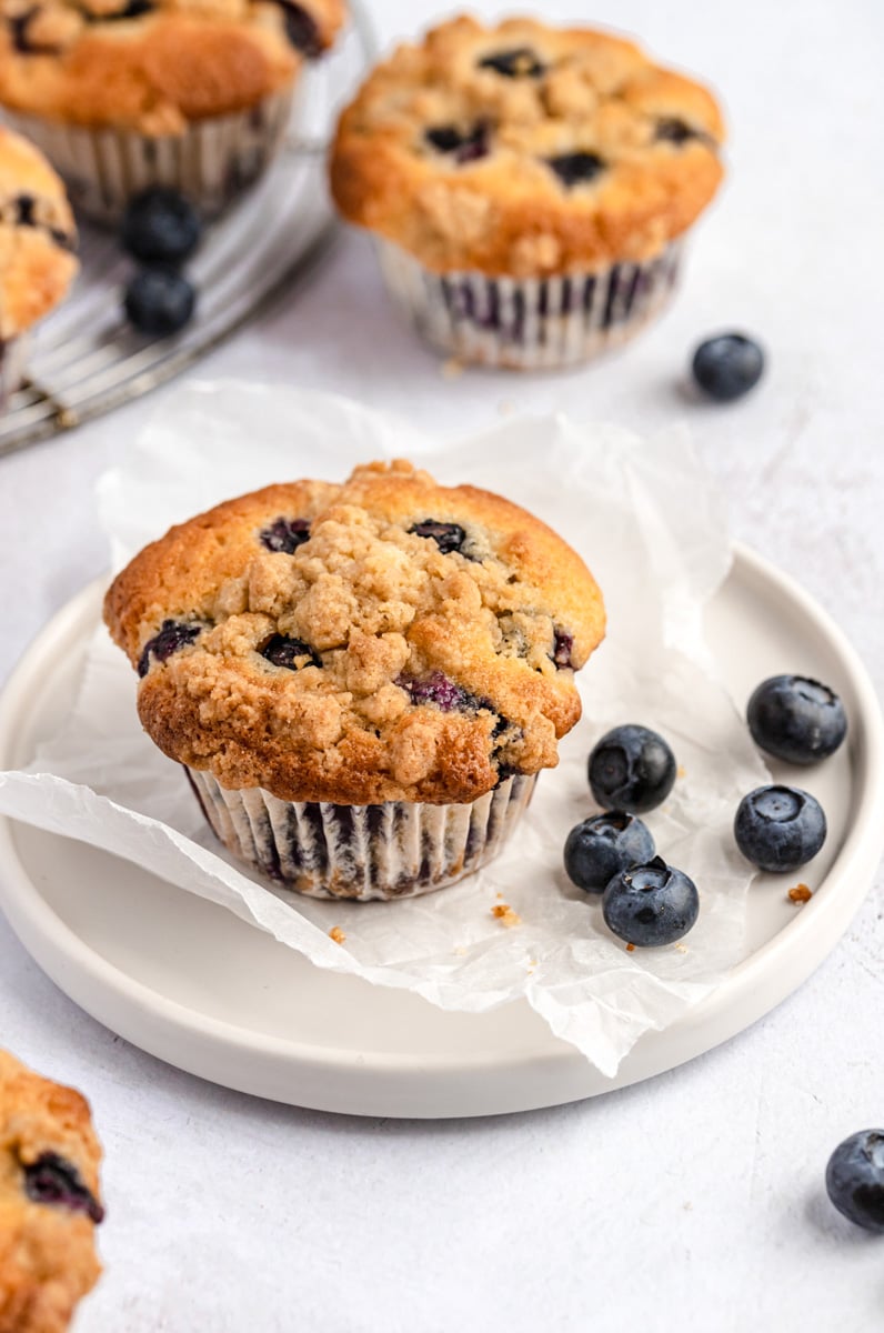 easy bakery style blueberry muffin on a plate with blueberries