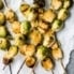 Spicy maple grilled brussels sprouts on skewers on top of parchment paper