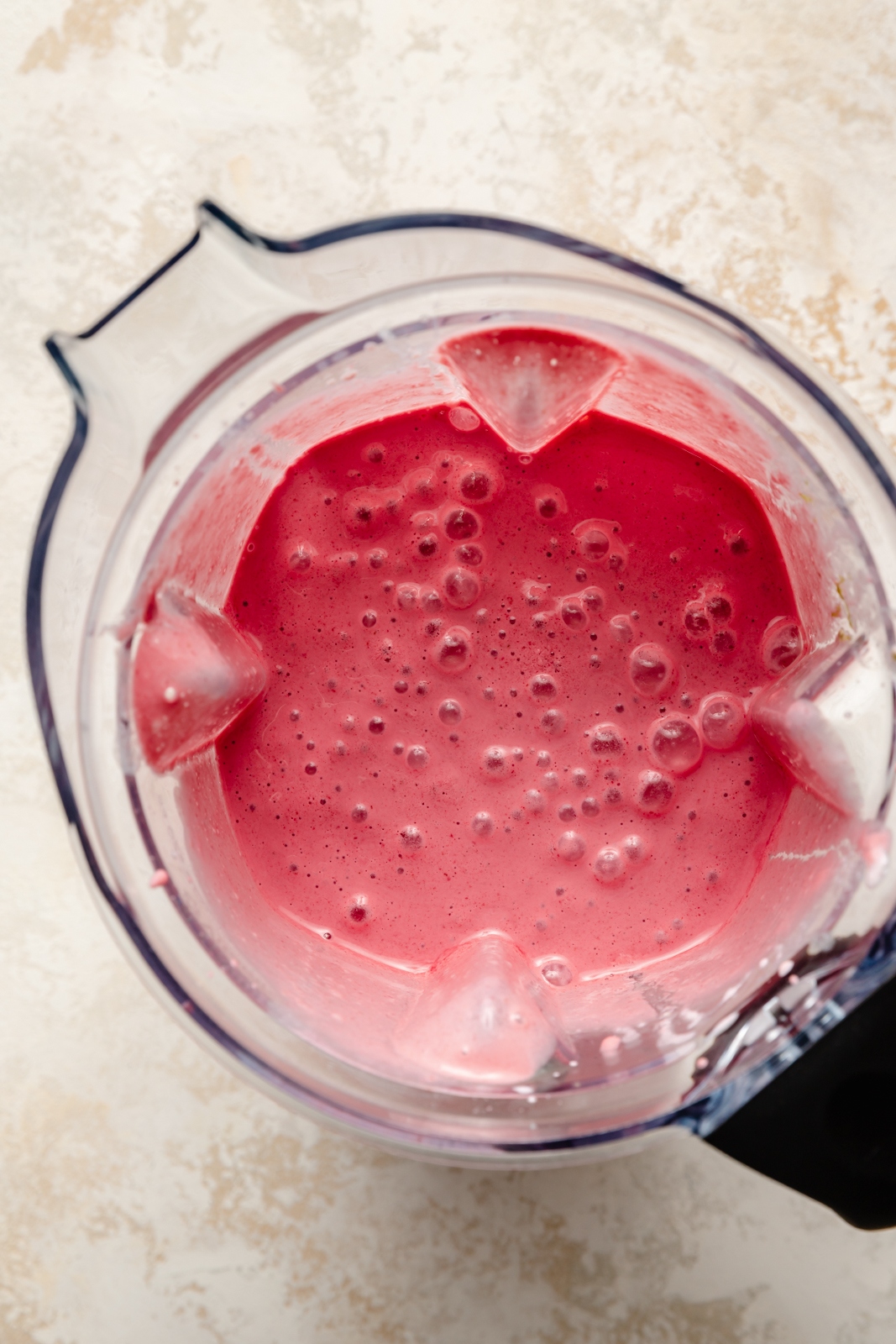 top-down view of a cherry lime smoothie in a blender