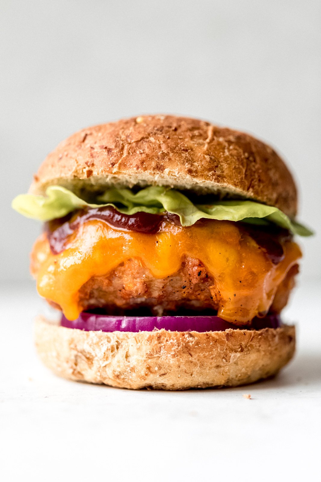 bbq chicken burger topped with lettuce, cheese, and bbq sauce