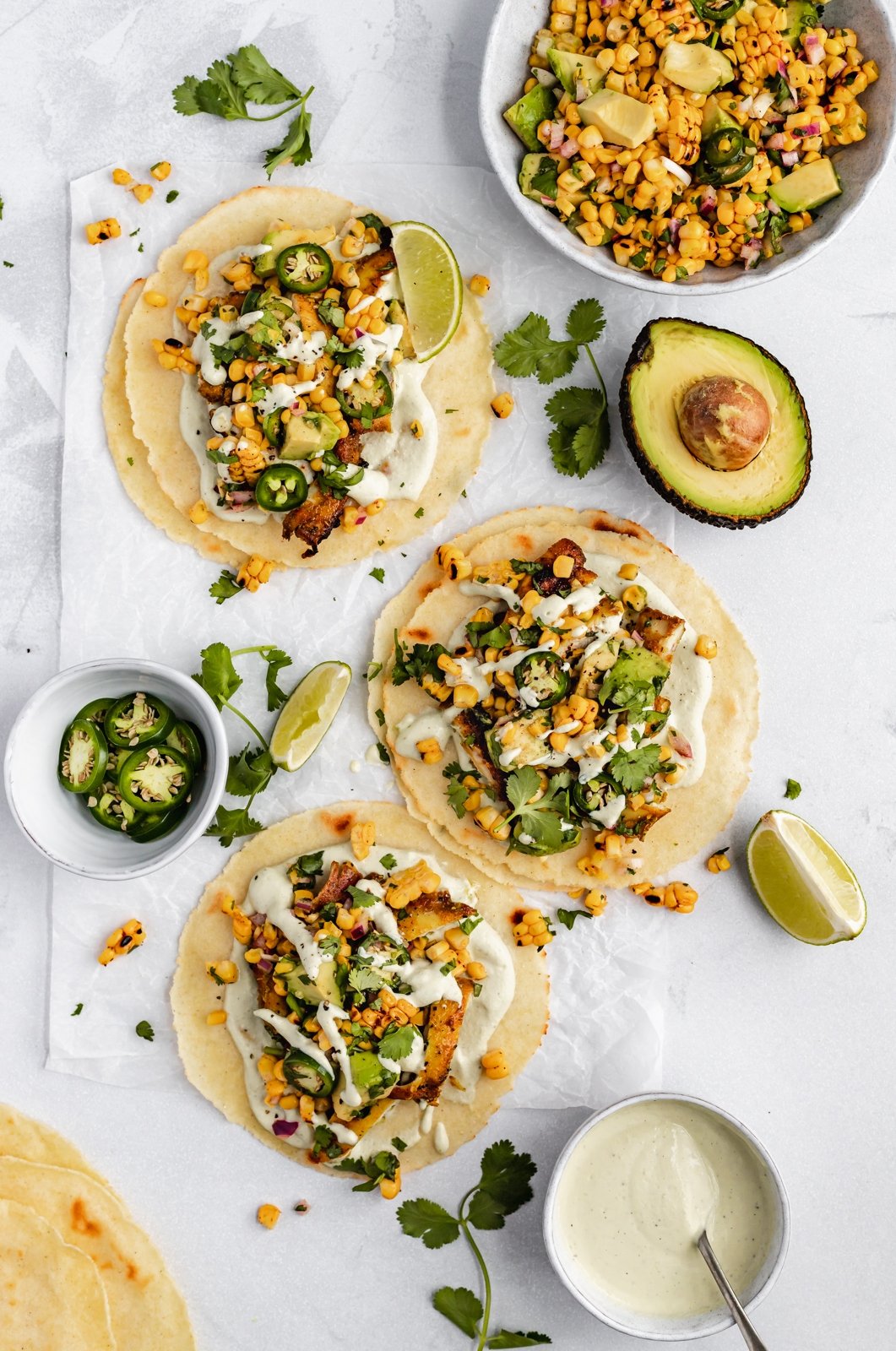 three grilled street corn chicken tacos on parchment paper