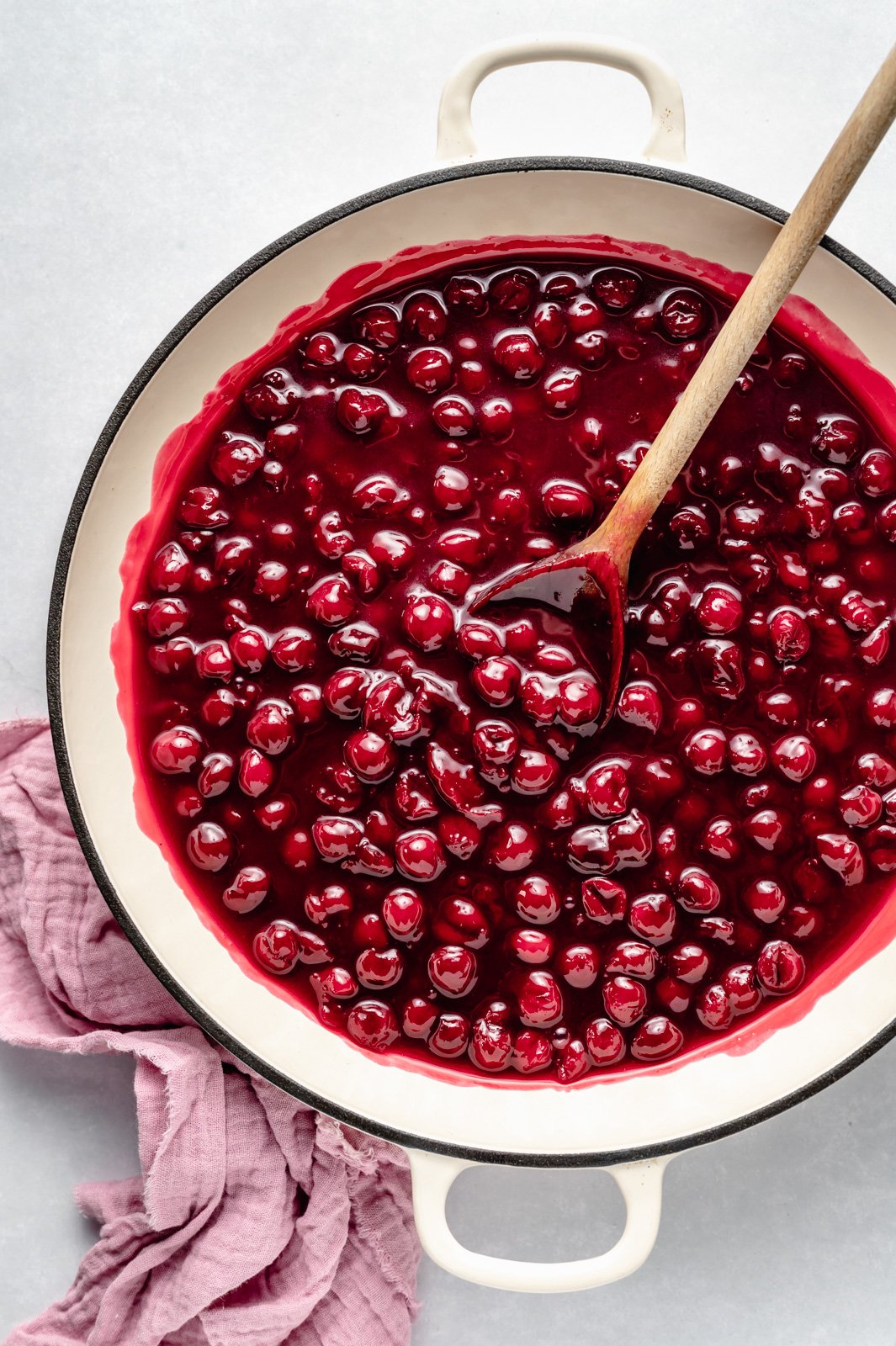 tart cherry pie filling in a pot with a wooden spoon