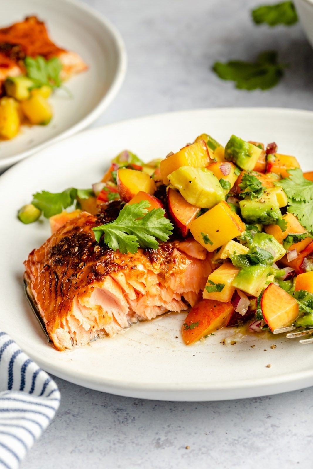 firecracker salmon on a plate topped with peach avocado salsa