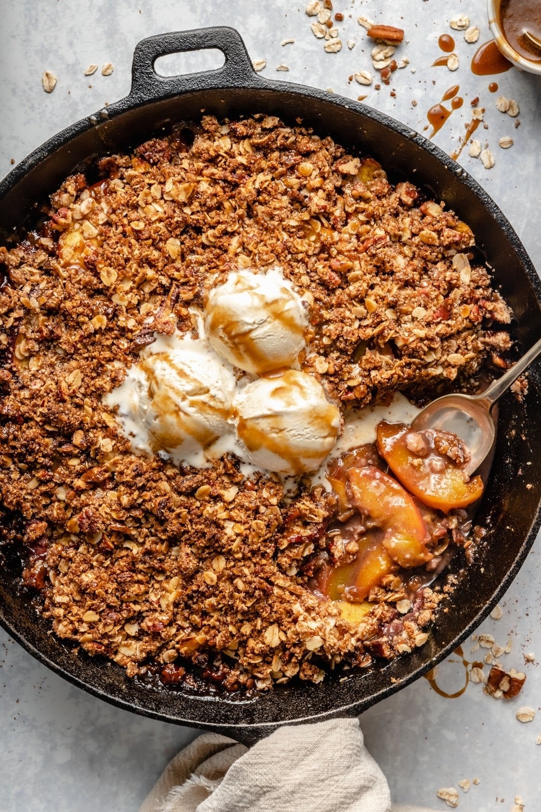 gluten free peach crisp in a skillet topped with ice cream