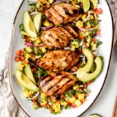grilled chicken on a plate with avocados and mangos