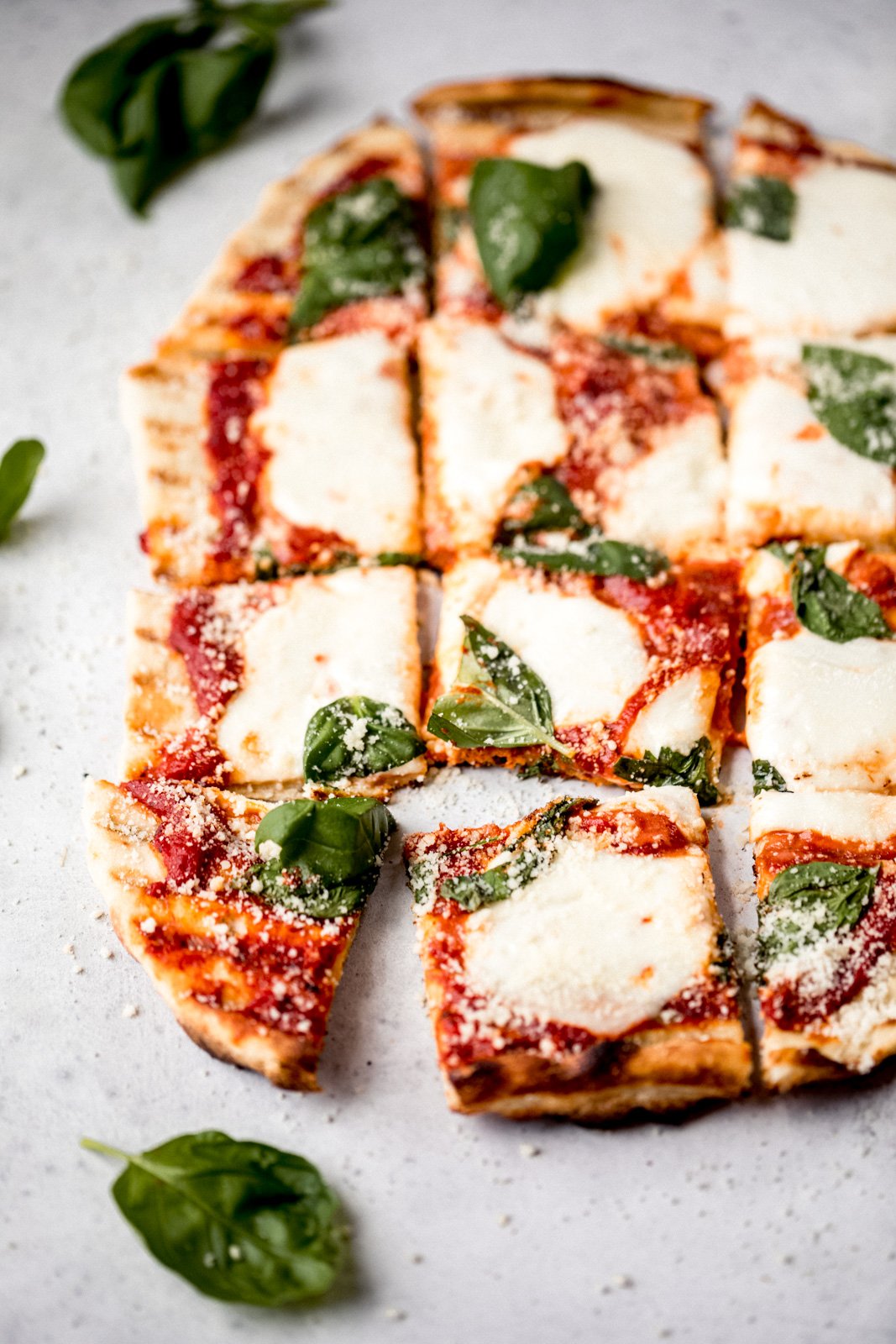 grilled pizza with cheese and basil cut into squares 