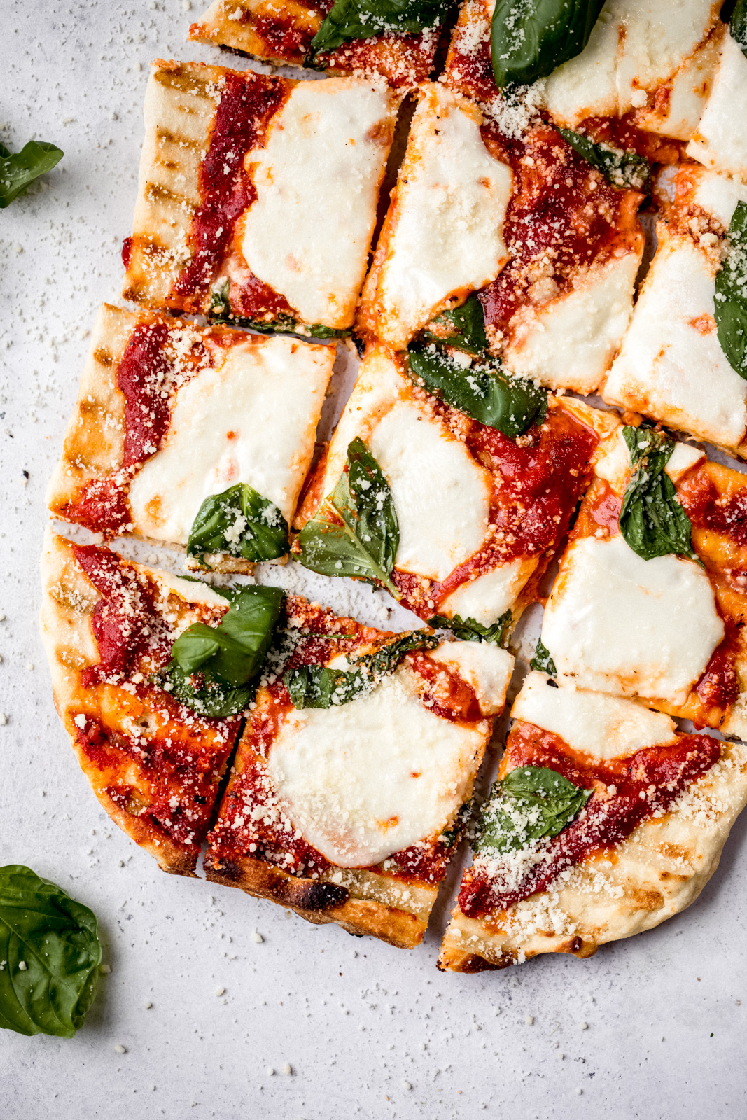 grilled pizza with cheese and basil cut into squares