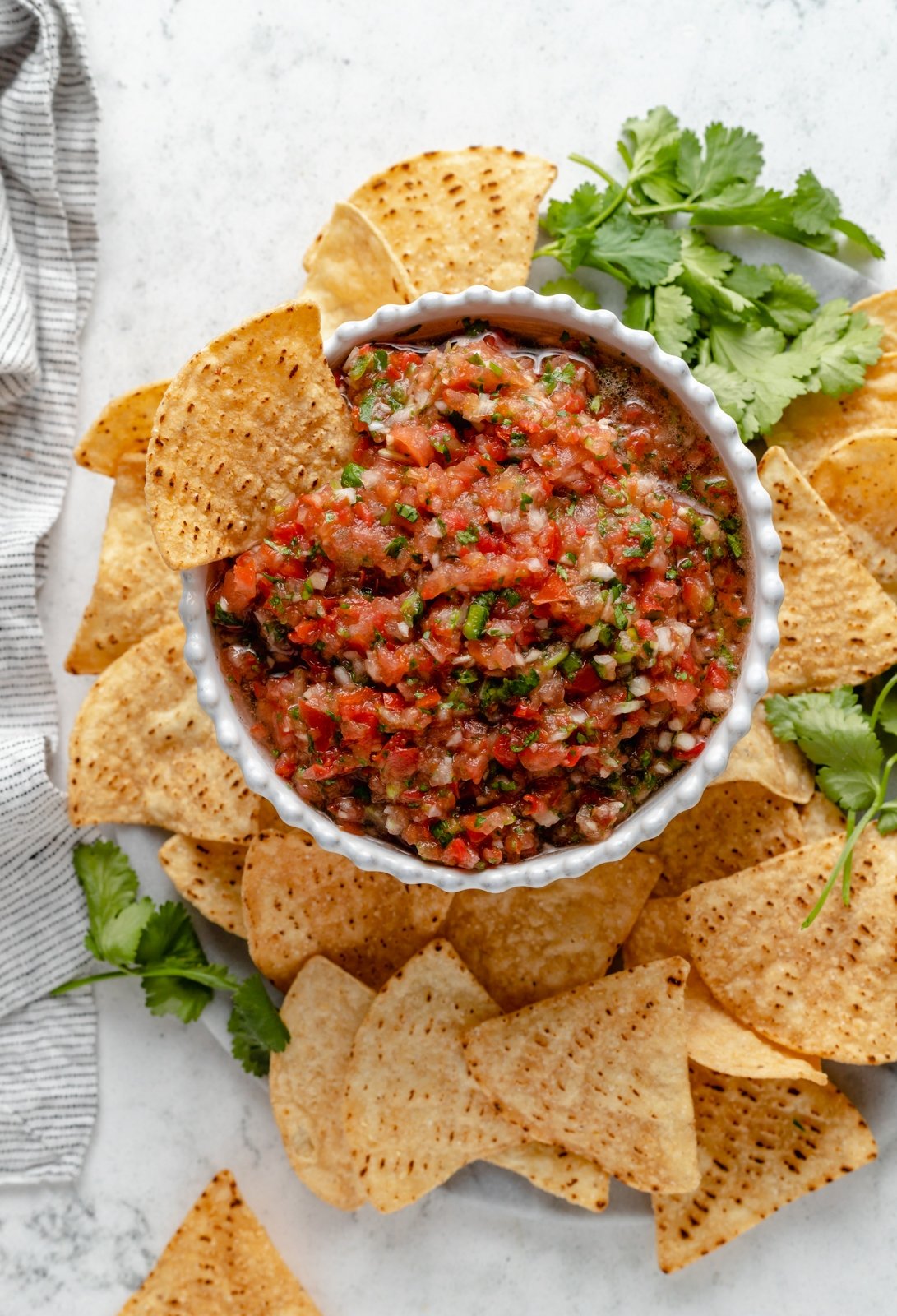 homemade salsa in a bowl surrounded by tortilla chips