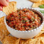 dipping a chip into homemade tomato salsa