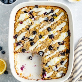 lemon blueberry baked oatmeal in a baking dish with a slice cut out
