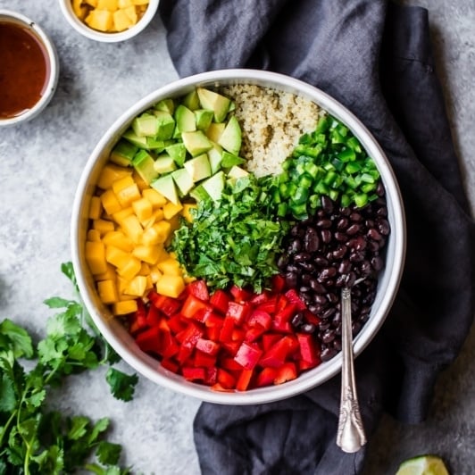 healthy mango black bean quinoa salad in a bowl with a spoon
