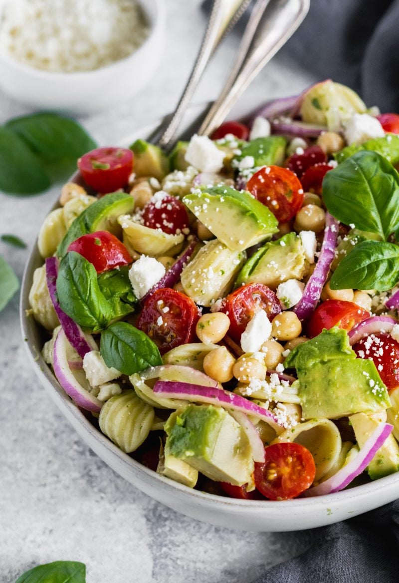 chickpea pasta salad with avocado, tomato, red onion and feta in a bowl