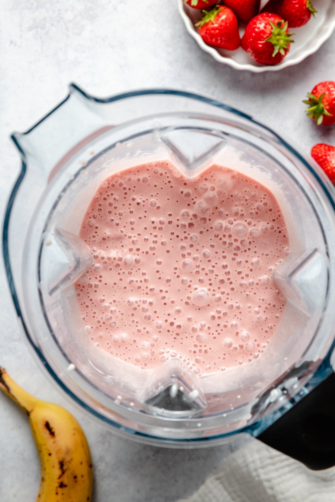 top-down view of a peanut butter banana strawberry smoothie in a blender
