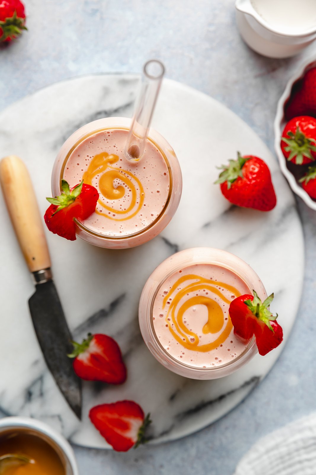 top-down view of two peanut butter strawberry banana smoothies in glasses