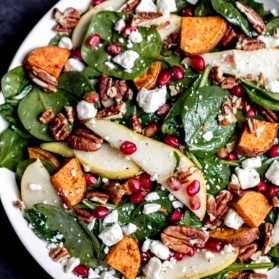 pomegranate spinach salad with sweet potato and pear in a bowl