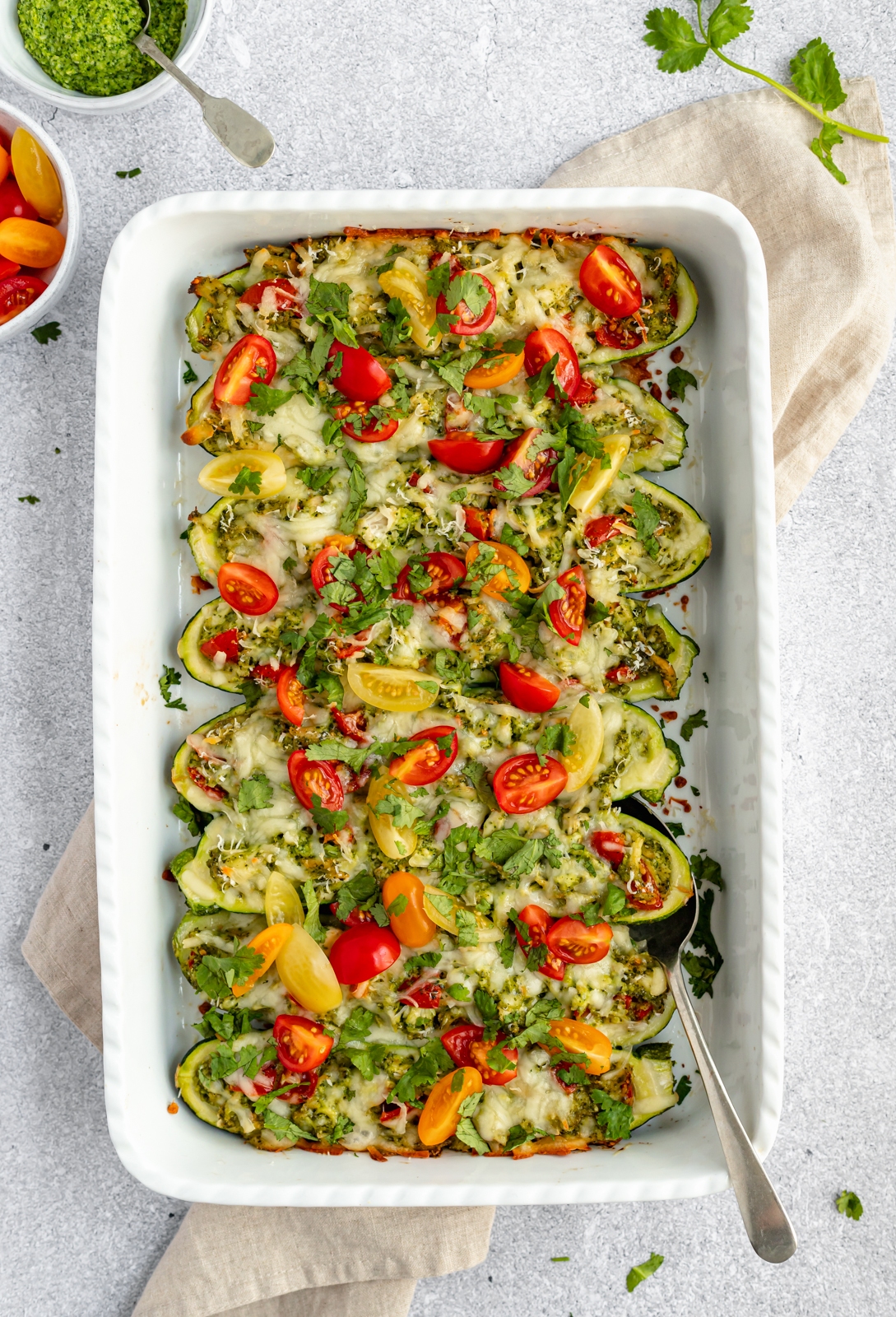 low carb pesto chicken stuffed zucchini boats in a baking dish