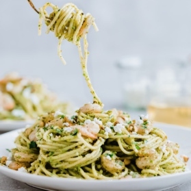 twirling shrimp pesto pasta up from a plate
