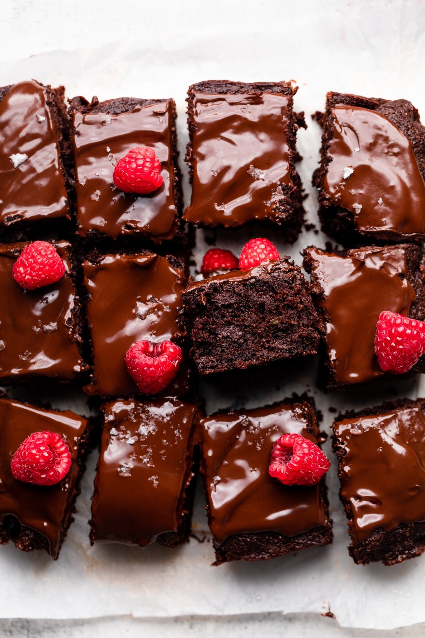 chocolate zucchini cake cut into squares and topped with raspberries