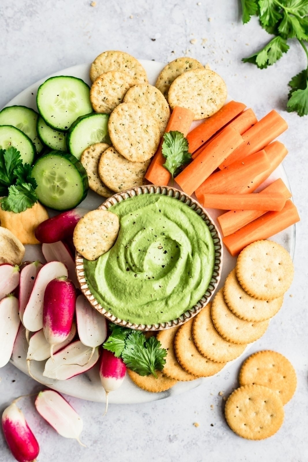 vegan green cashew dip on a platter with veggies and crackers