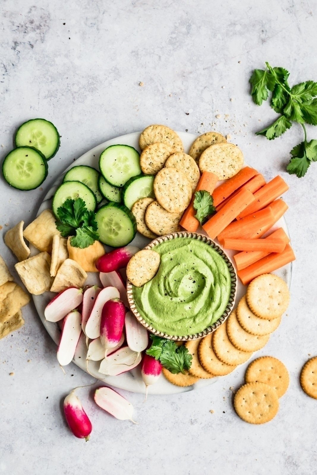 spicy green vegan cashew dip on a platter with veggies and crackers