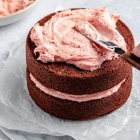 frosting a cake with strawberry buttercream frosting