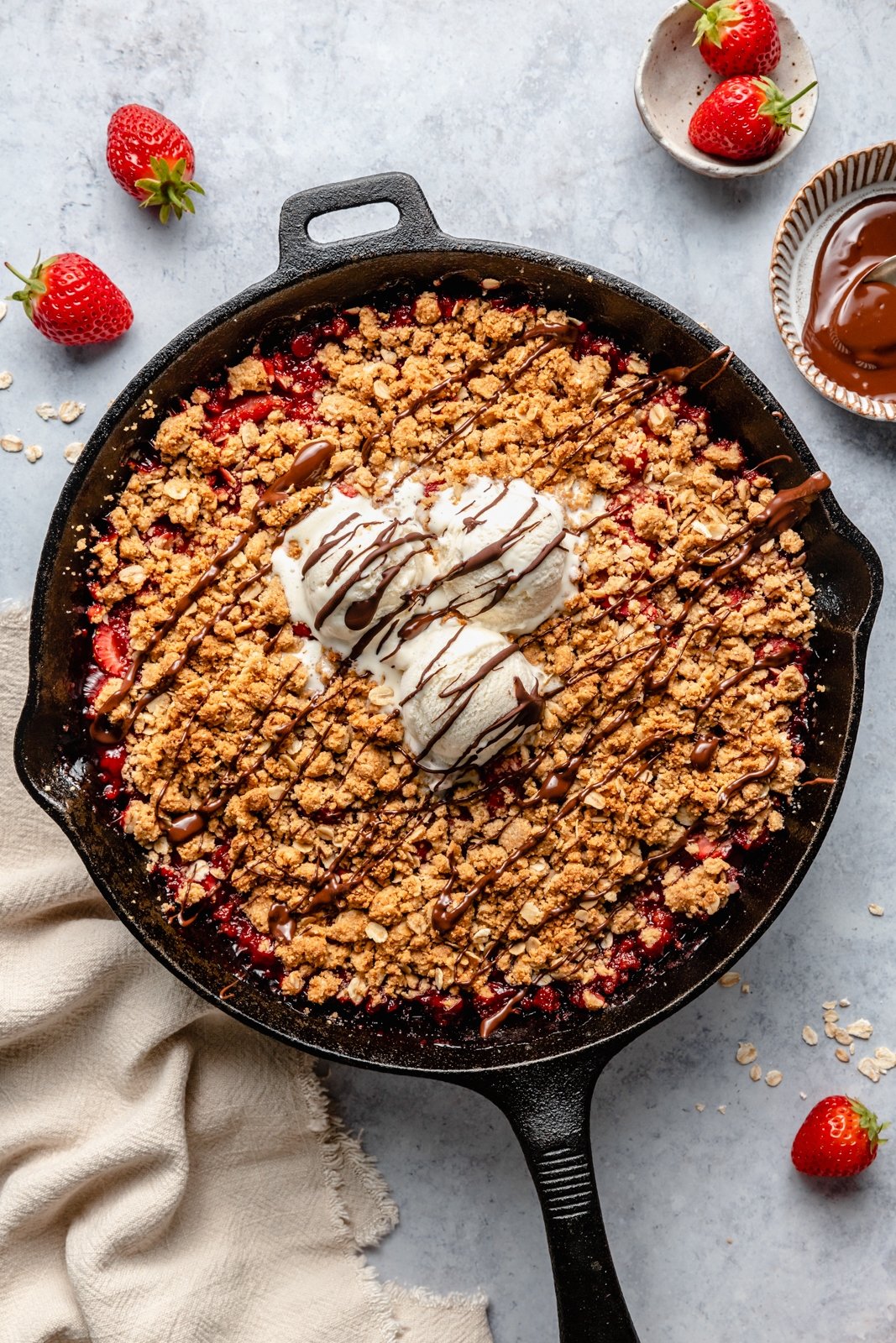 strawberry crisp in a skillet topped with ice cream