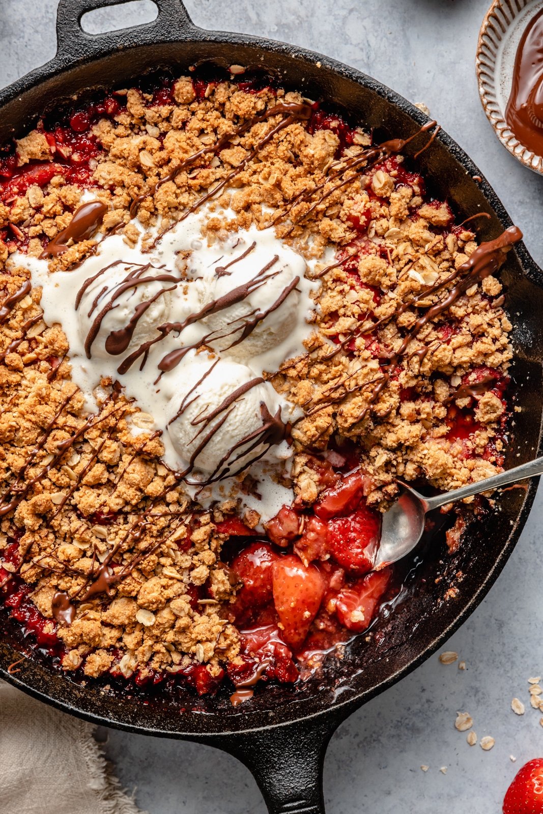 easy strawberry crisp in a skillet topped with ice cream and chocolate