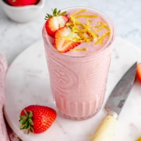strawberry lemonade smoothie in a glass topped with strawberry slices