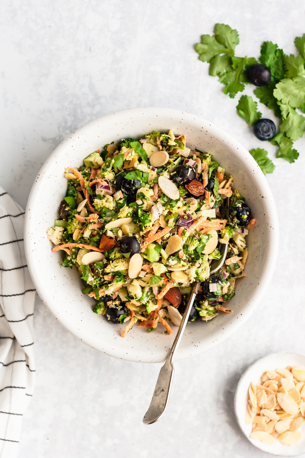 healthy vegetarian broccoli salad in a white bowl with a spoon
