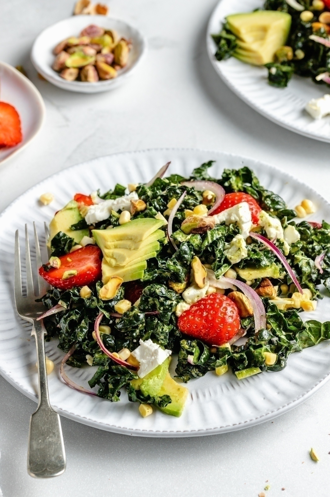 strawberry kale salad on a plate with a fork