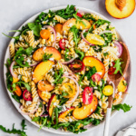arugula pasta salad with peaches in a bowl