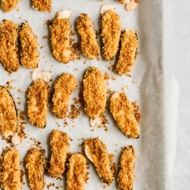 Tortilla chip crusted baked jalapeño poppers on a baking sheet