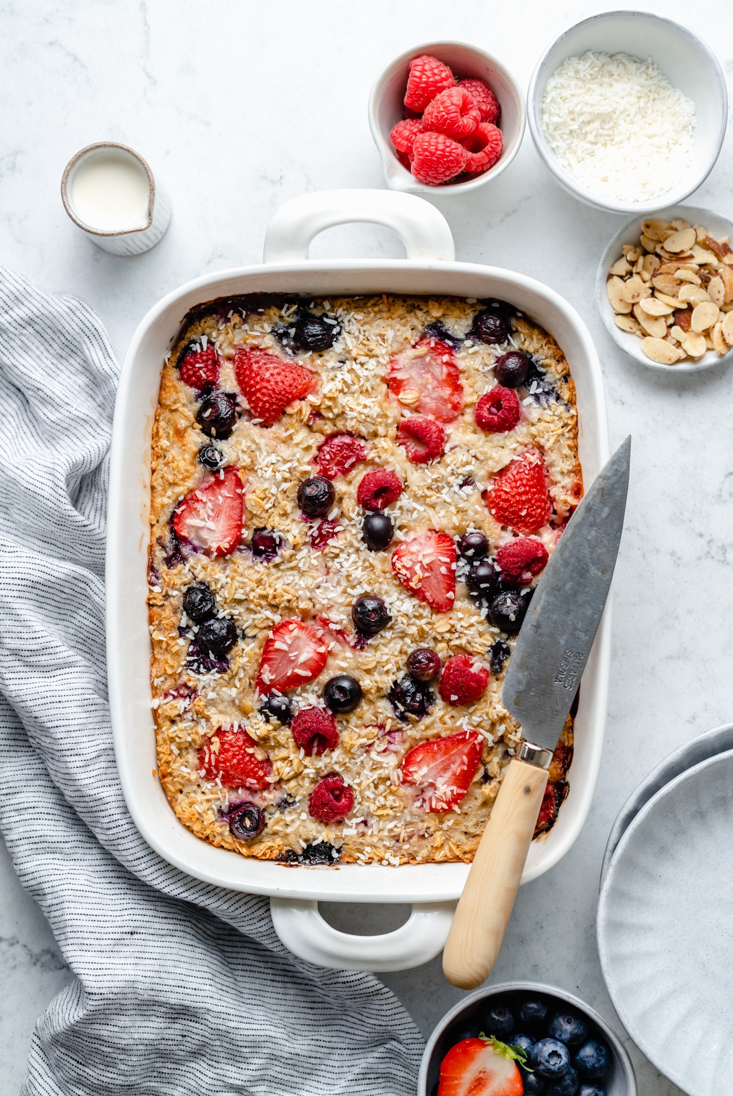 berry oatmeal bake in a baking dish with a knife