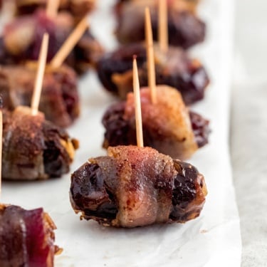 bacon wrapped dark chocolate and goat cheese stuffed dates on wax paper