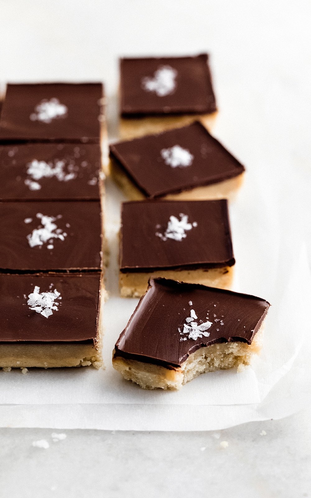 healthy millionaire bars topped with sea salt on parchment paper