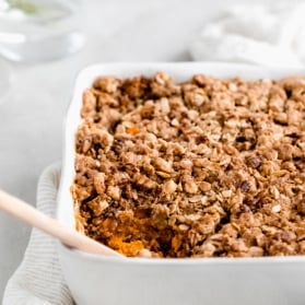 healthy sweet potato casserole in a baking dish with a wooden spoon