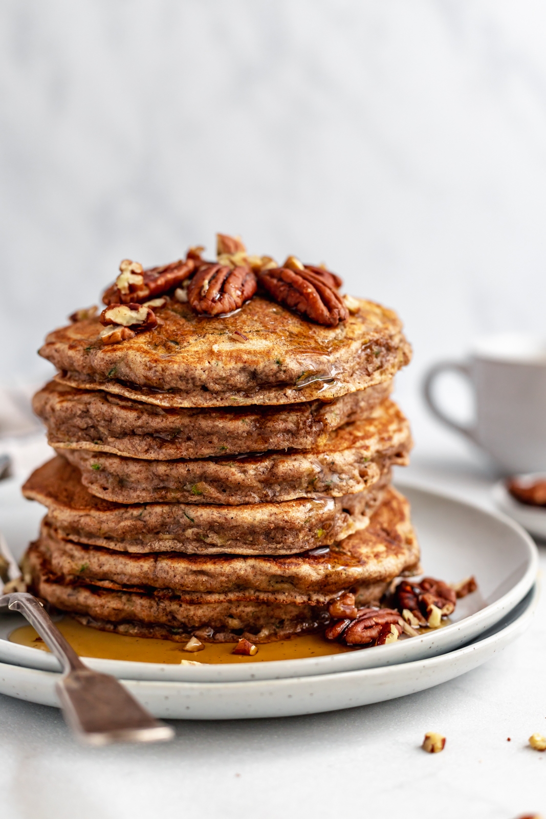 stack of healthy zucchini pancakes on a plate topped with pecans