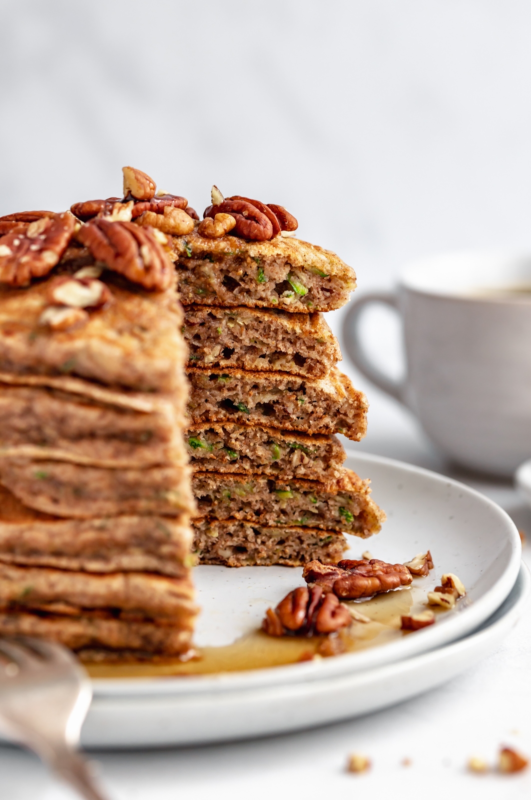 stack of whole wheat zucchini bread pancakes with a bite taken out on a plate