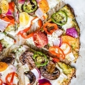 low carb zucchini pizza crust topped with cheese and veggies cut into slices